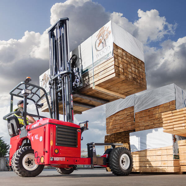 Moffett truck mounted forklift lifting timber high to stack